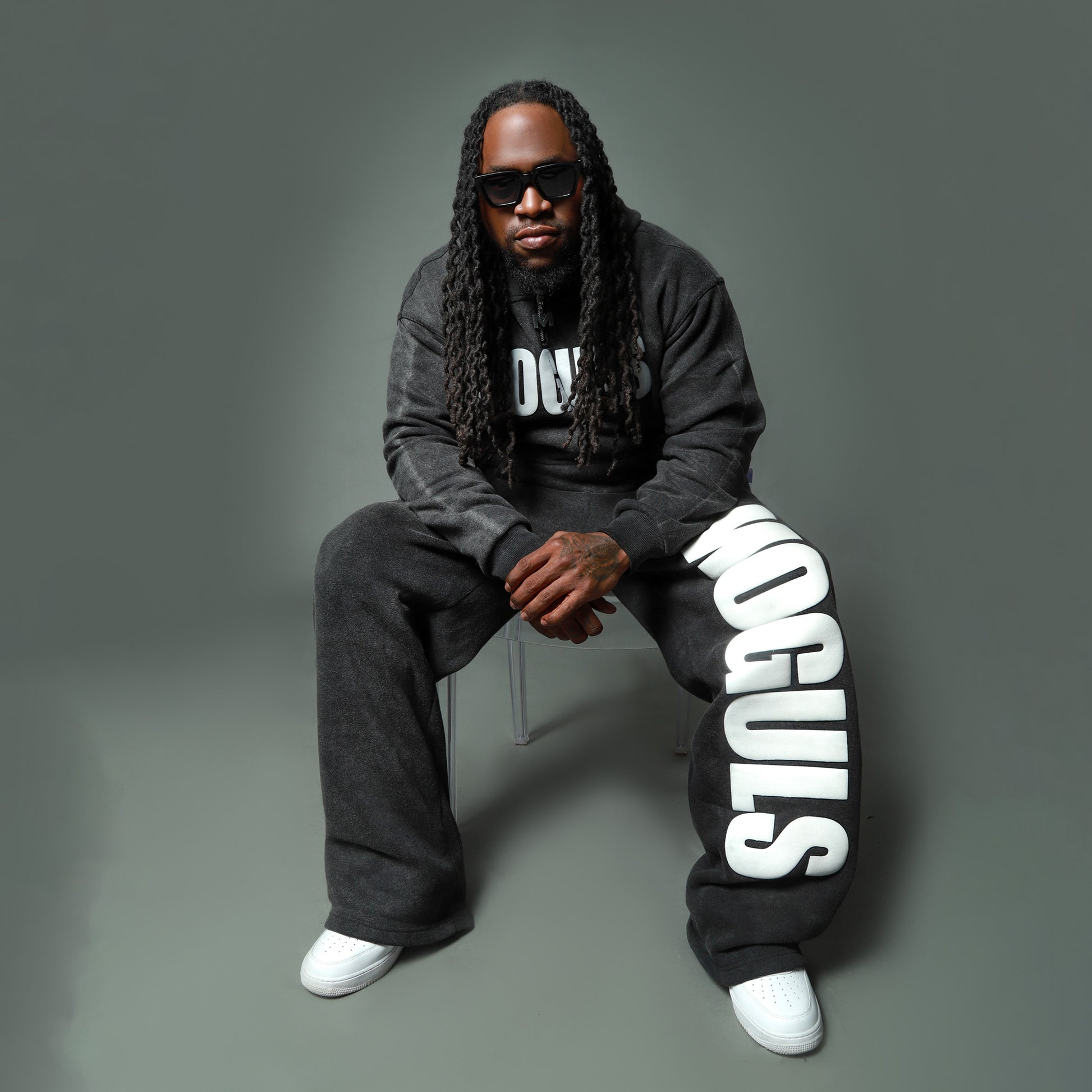 Seated model wearing black 4 Moguls Oversized Sweatsuit highlighting oversized fit and relaxed silhouette